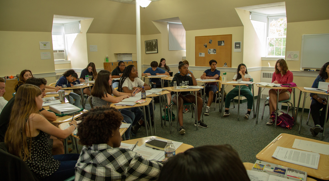 a diverse group of students seated at their desks participating in a discussion
