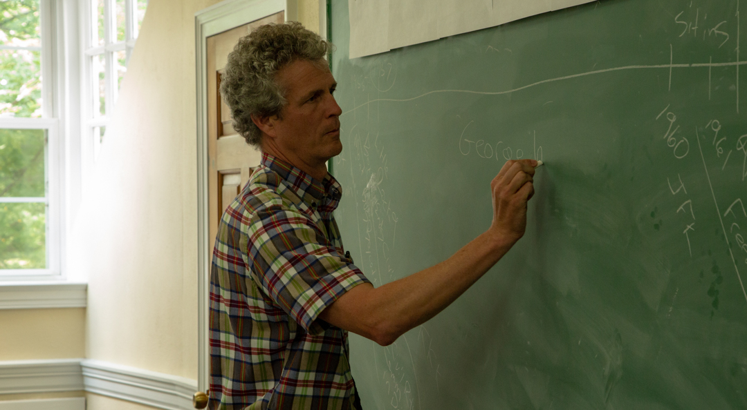 male teacher writing on the chalkboard